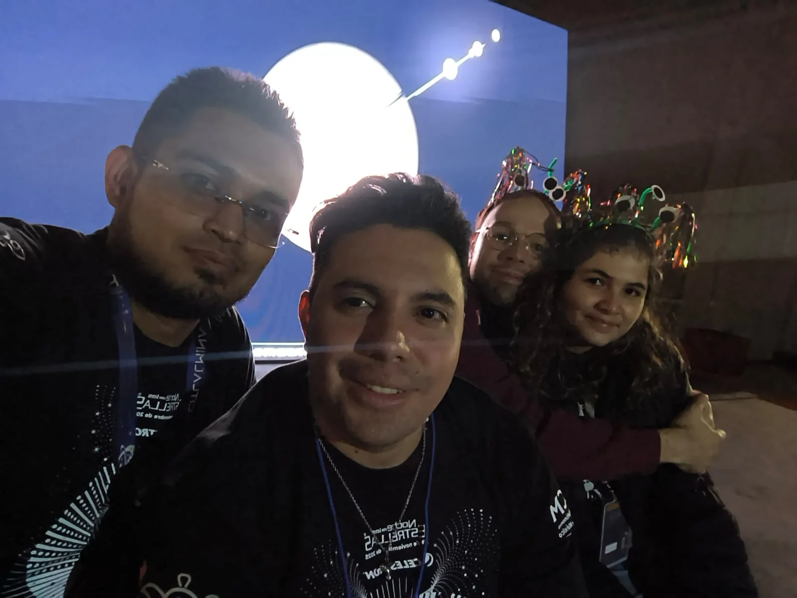 Tres participantes frente a una proyección astronómica.